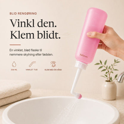 Hand squeezing the pink 350 ml Relievoo peri bottle with its angled nozzle over a basin rvpumpen rvhasar