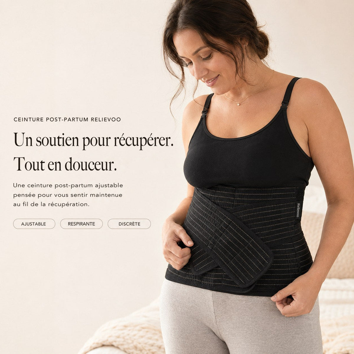Femme portant la ceinture de maintien post-partum Relievoo noire sur un débardeur noir, la main sur la sangle avant