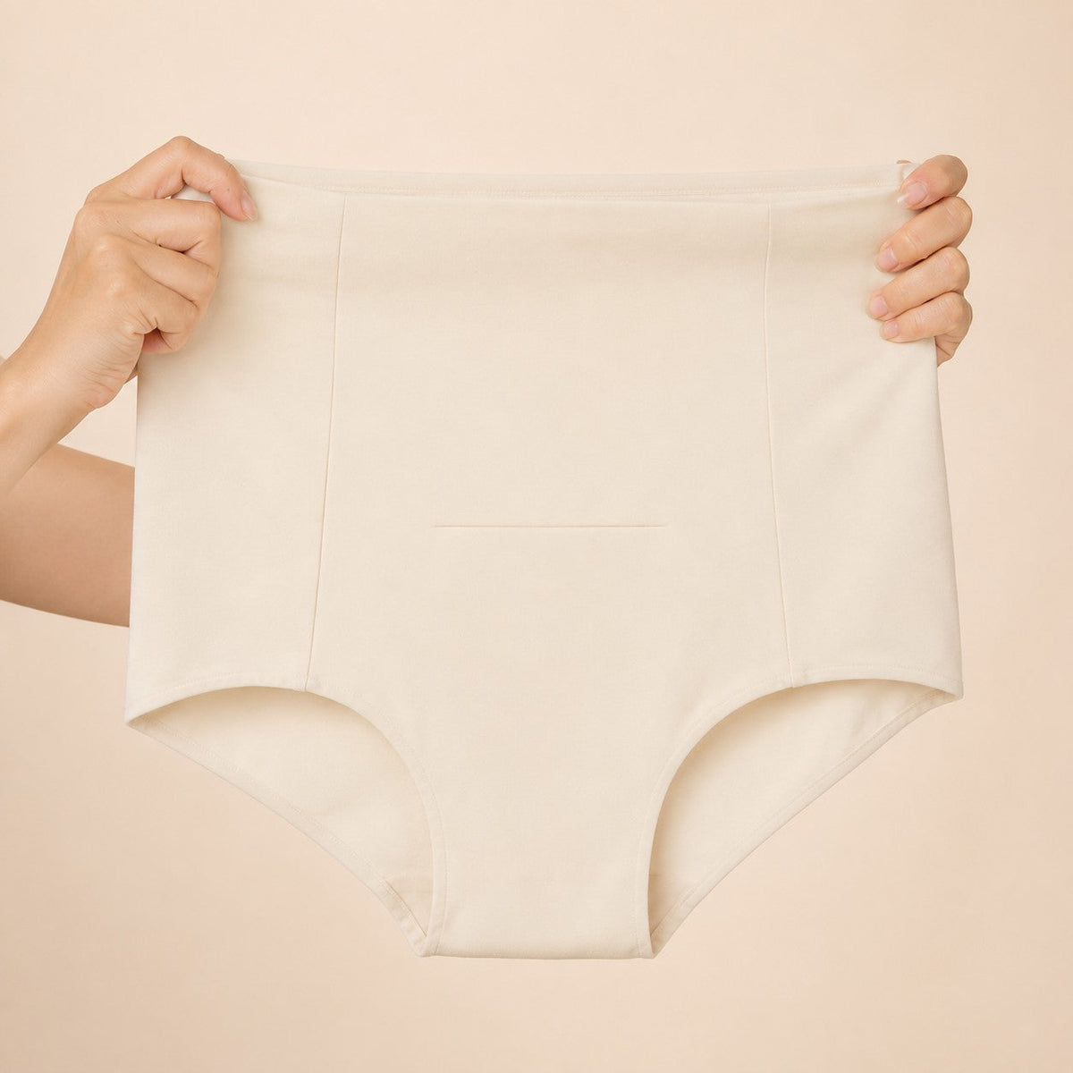 Hands stretching the ivory postpartum soothing brief to show the soft high waistband