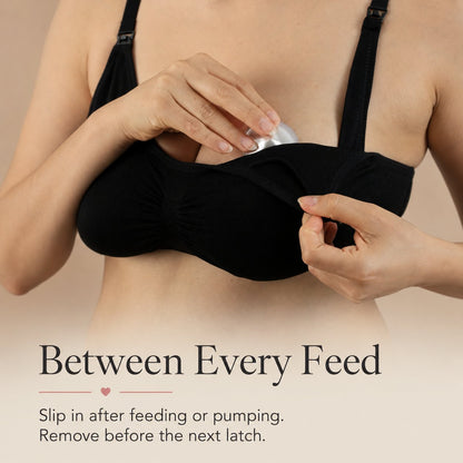 Mother in a black nursing bra easing a silver nursing cup back into place after a feed rvpumpen rvhasar